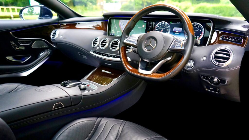 Sleek luxury car interior showcasing modern dashboard and leather seating, emphasizing comfort and style.