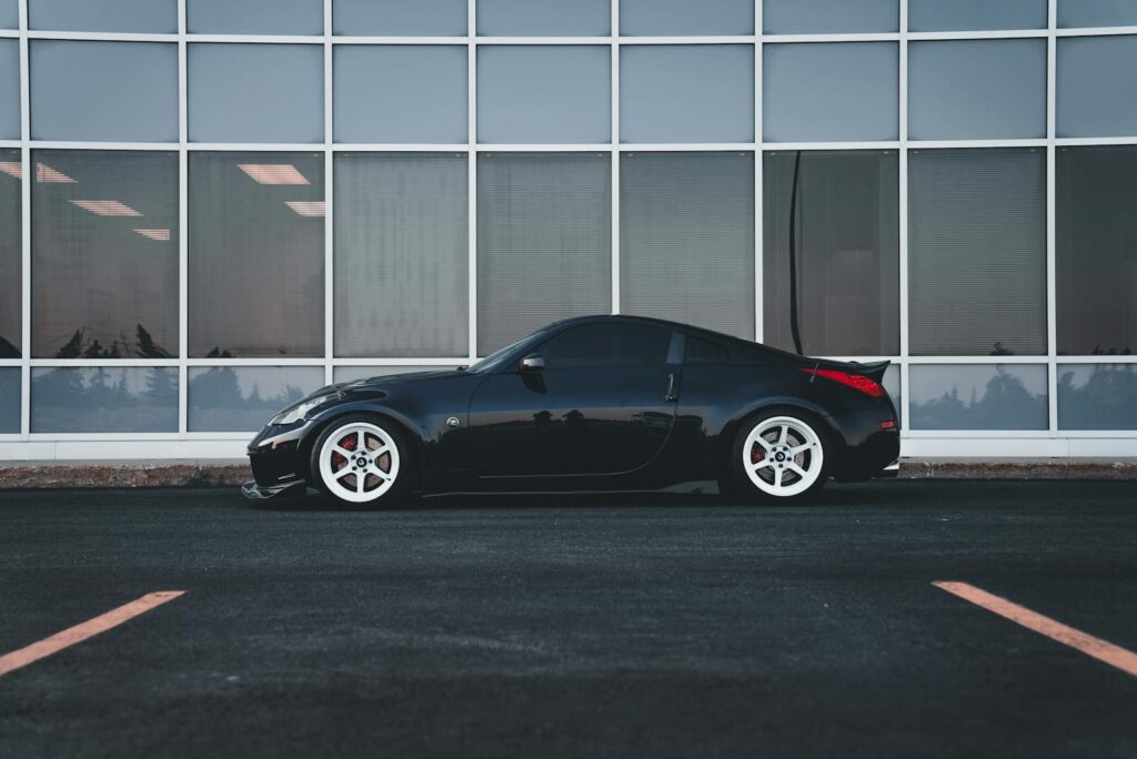A stylish black car parked in front of a modern urban building.