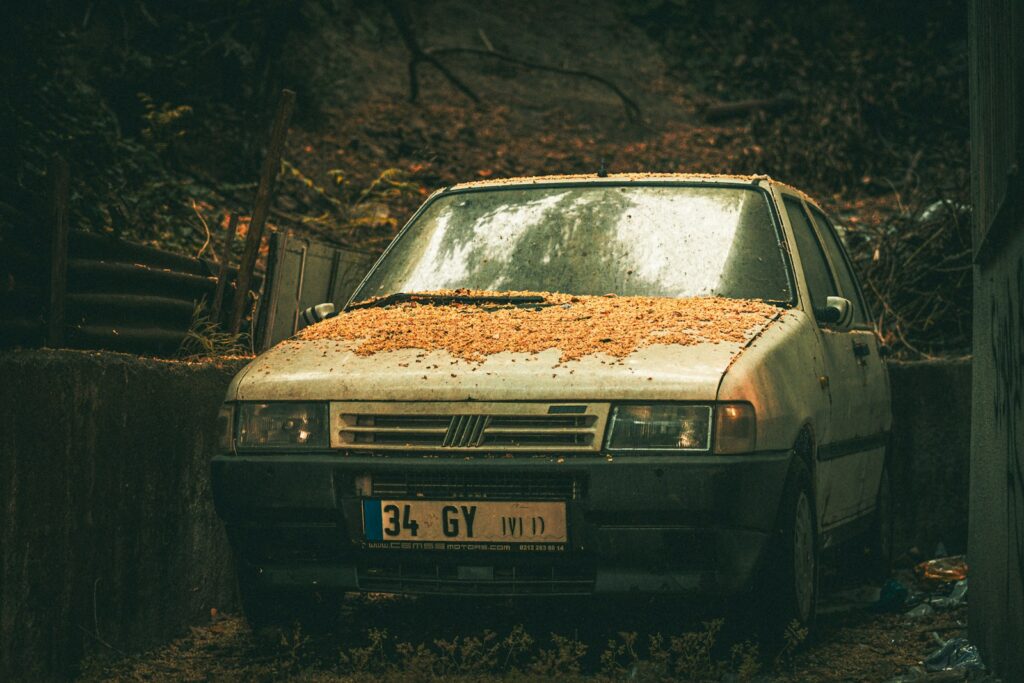 An old car is parked in the mud