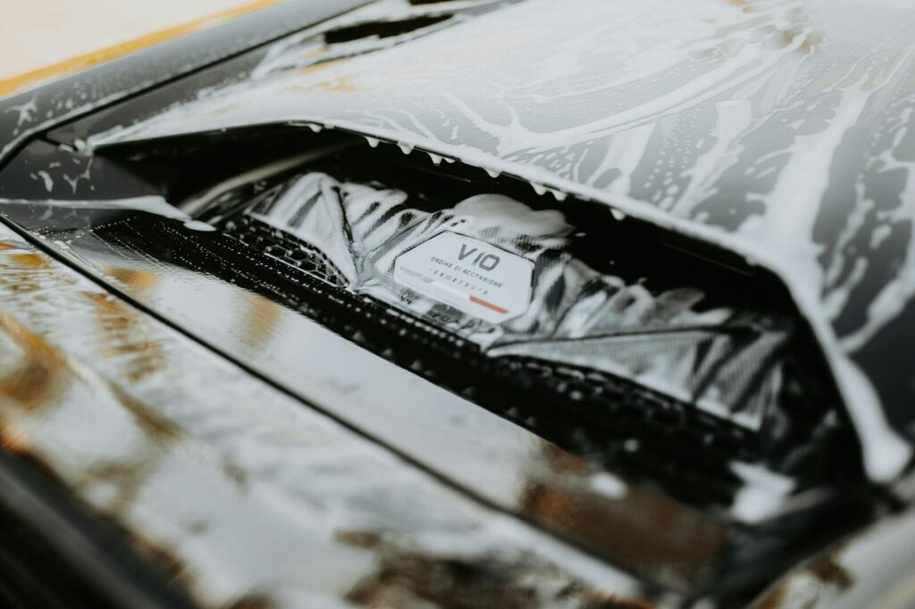 Detailed image of a sleek car being washed with foam, showcasing the car's design and cleanliness.