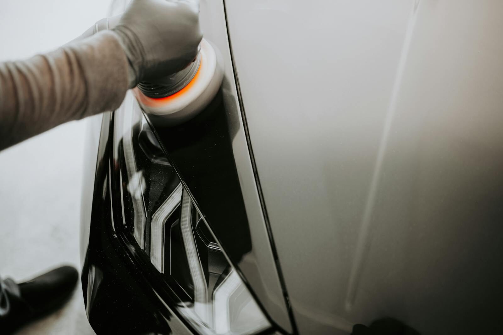 Photo by Luke Miller Close-up view of a person polishing a black car using a buffing machine.