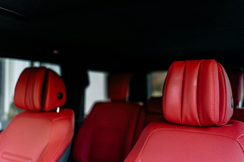Close-up view of a luxury car interior with red leather seats and headrests.