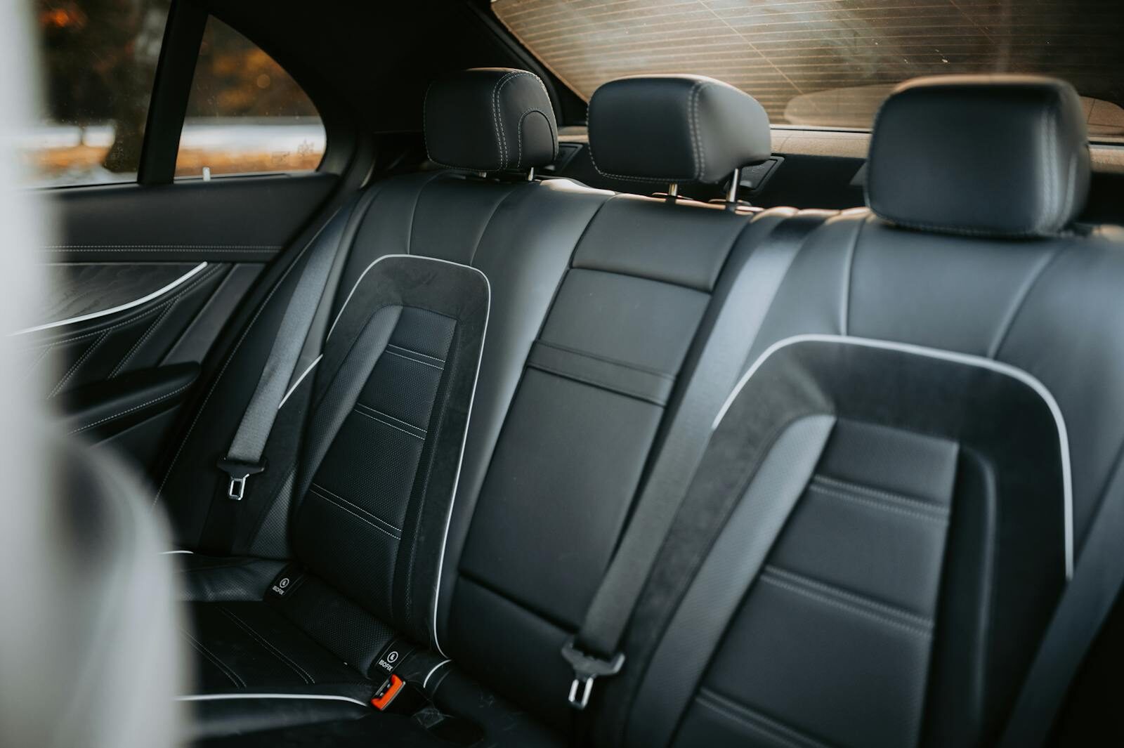 Elegant black leather car interior showcasing spacious and luxurious backseat design.