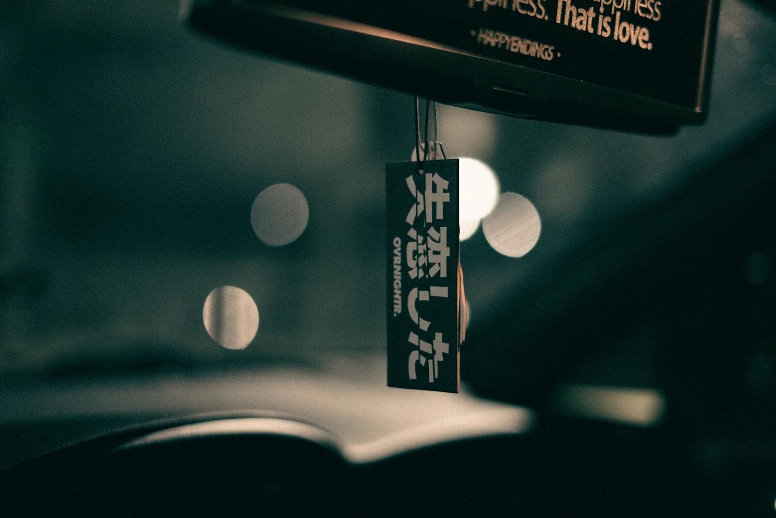 Artistic car interior with a hanging air freshener, captured with bokeh effect at dusk, creates a moody ambiance.