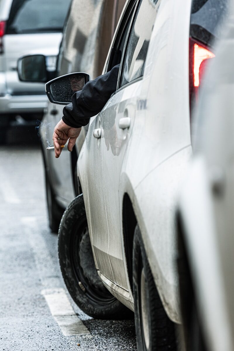 A person is smoking while stuck in traffic.