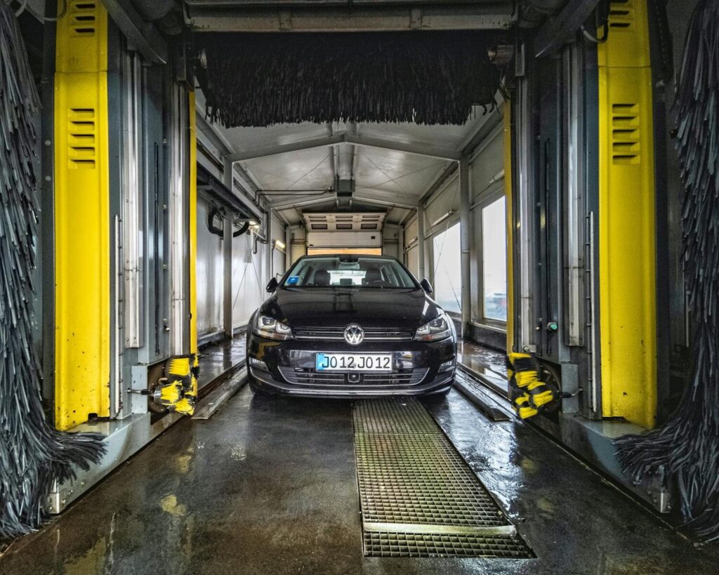 A black car undergoing a thorough cleaning in an automated car wash facility.
