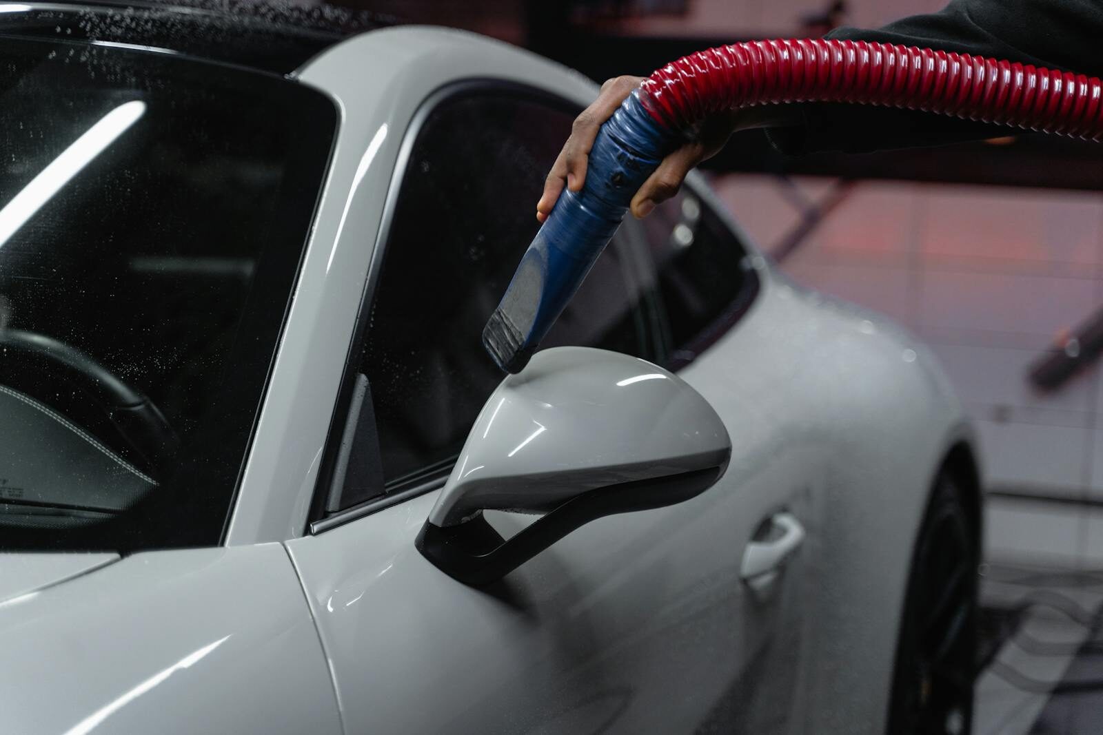 Photo by Tima Miroshnichenko A white sports car is meticulously vacuumed indoors for a flawless shine and maintenance.