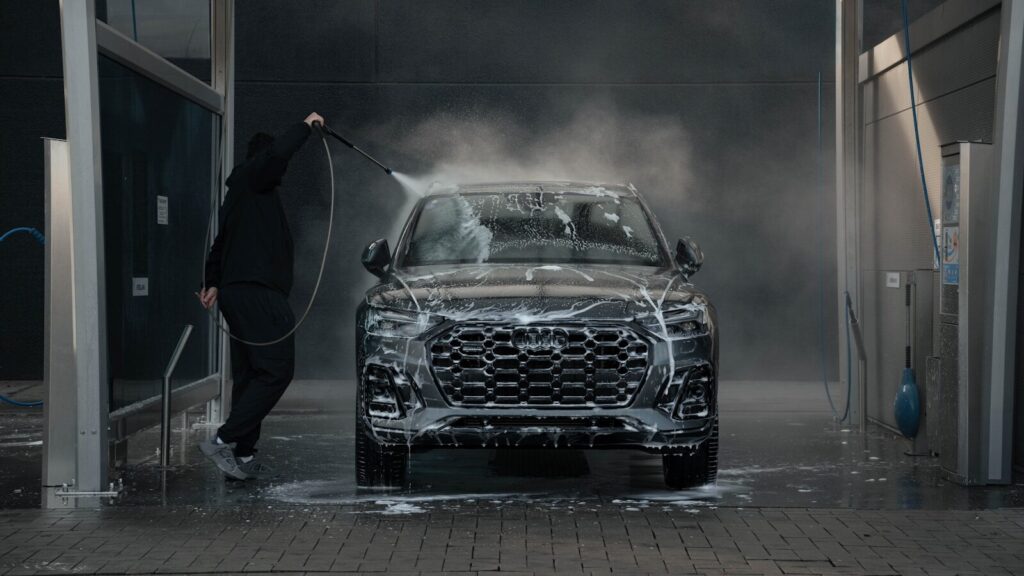 Person washing a black car with soap and water.