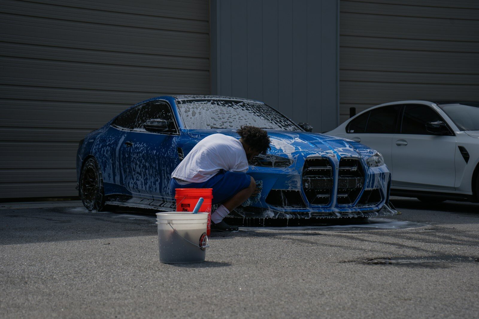 Photo by Archivio Automobile A person is washing a blue car with soap.