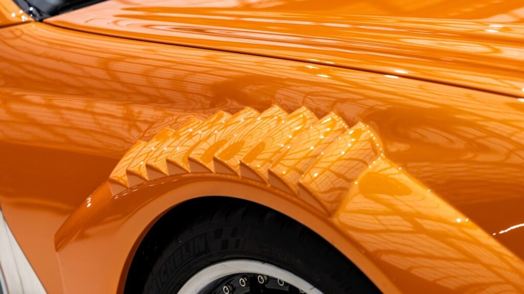 A close up of a car's shiny orange paint
