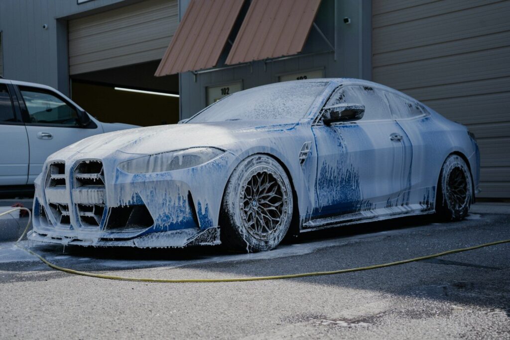 A blue car is covered in soap suds.