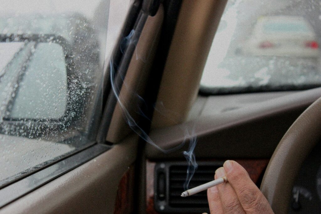 A person smoking a cigarette in a car