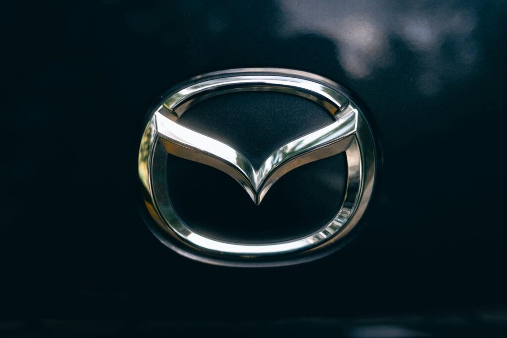 Close-up of a shiny metallic car logo on a dark surface.